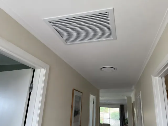 Ceiling return-air grille in a narrow hallway with white trim and beige walls in Maudsland